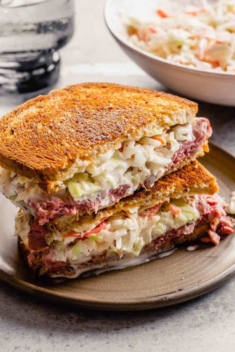 A sandwich with coleslaw inside on a brown plate.