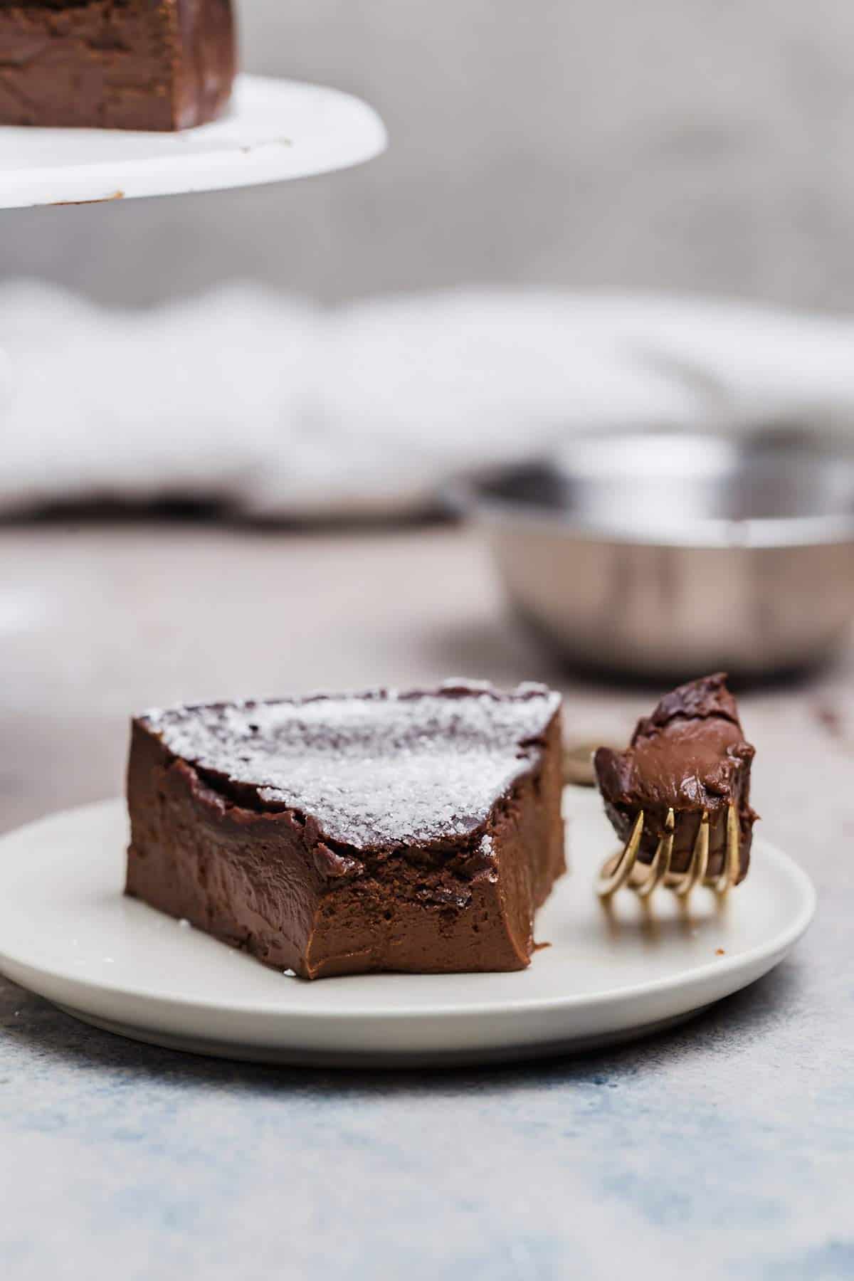 A slice of flourless chocolate cake with a forkful taken out.