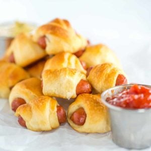 Mini hot dogs wrapped in crescent rolls on parchment paper.