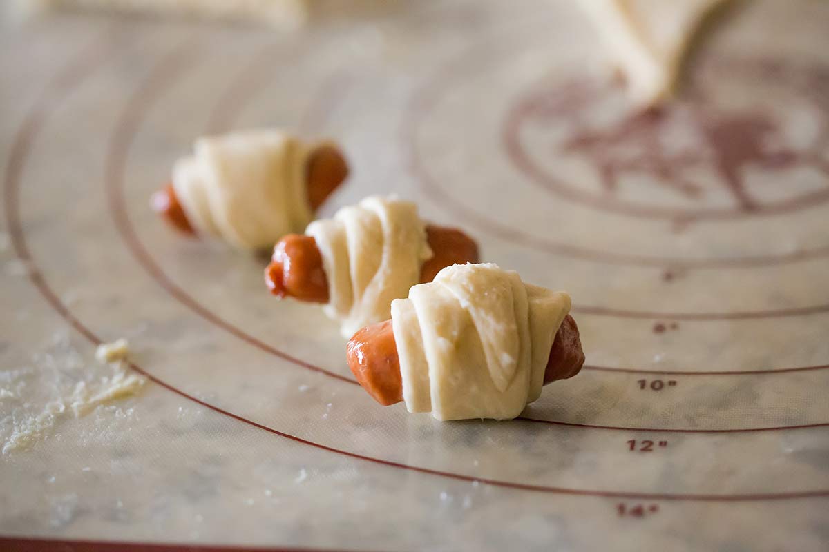 Mini hot dogs rolled up in crescent roll dough.