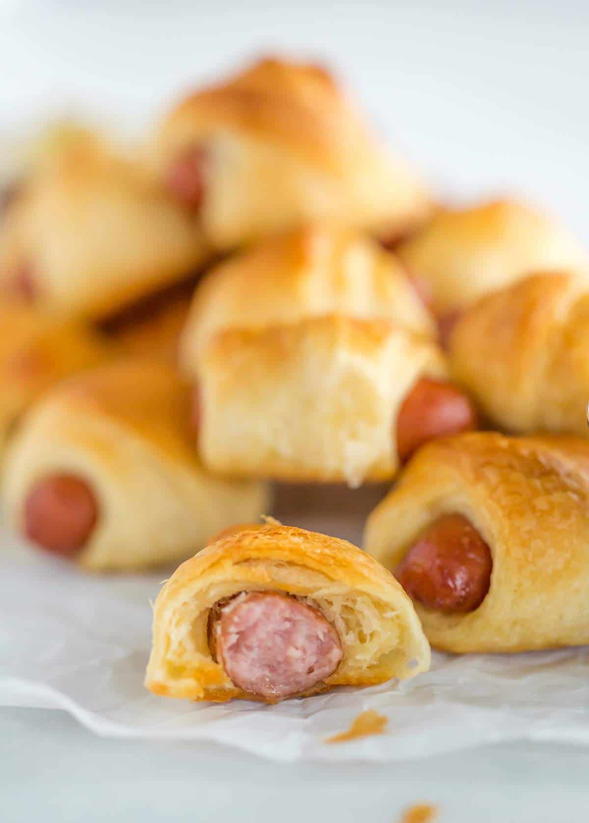 A stack of pigs in a blanket with one bitten into.