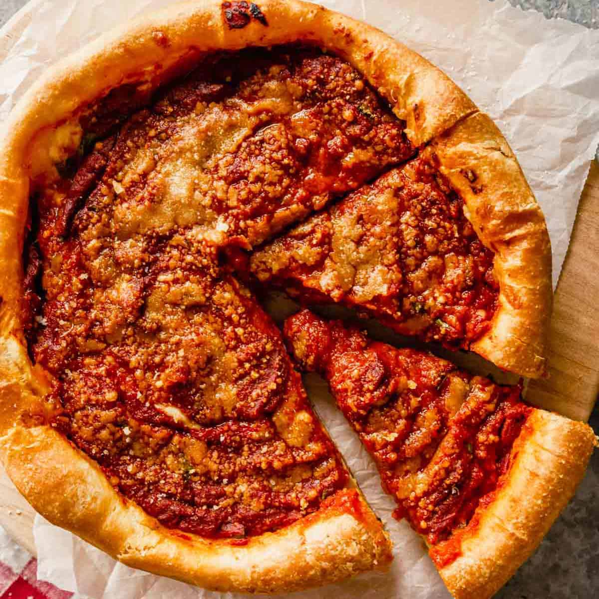 A close up of a deep-dish pizza with two slices cut out on a piece of parchment paper.