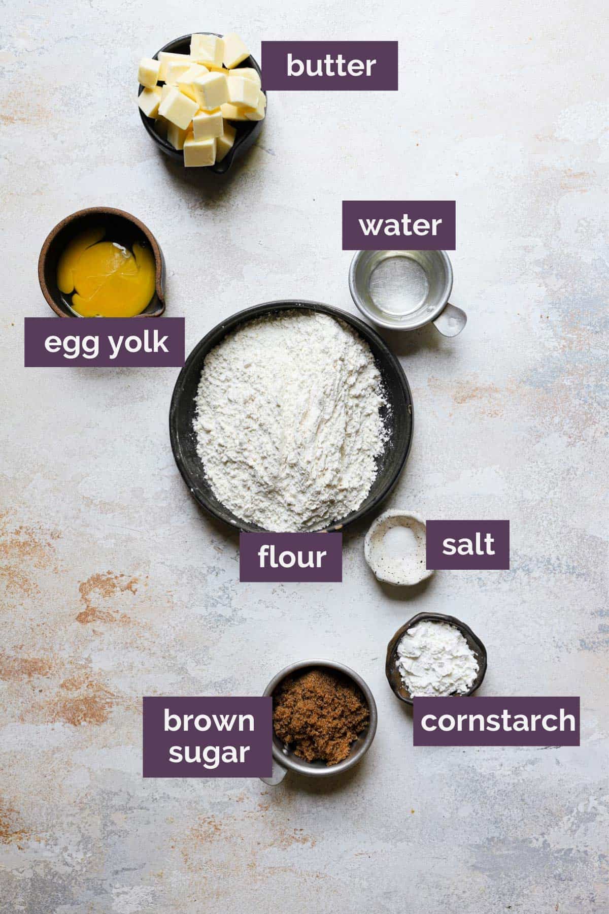 The ingredients for the shortbread crust in bowls with purple labels naming each ingredient.