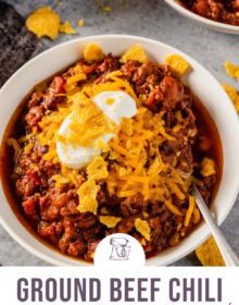 A white bowl of ground beef chili topped with cheese and sour cream with the words Ground Beef Chili the best ever at the bottom.