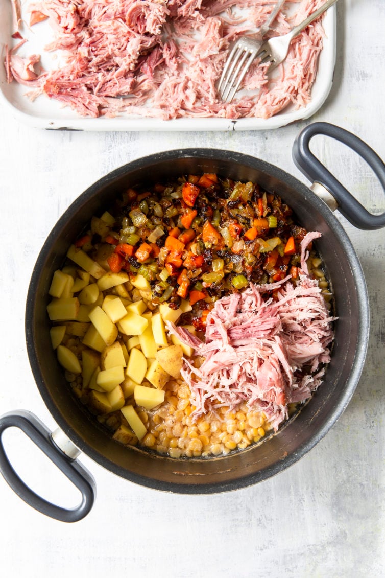Soup ingredients in Dutch oven and shredded ham on platter