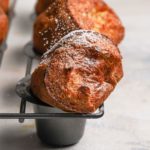 Golden brown baked breakfast popovers in a grey popover baking pan dusted with powdered sugar