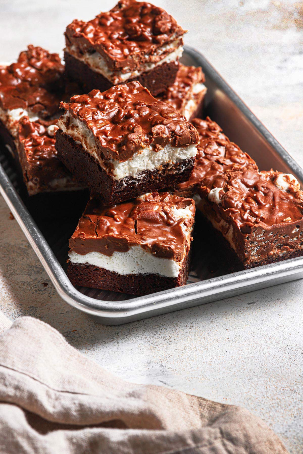 a stack of these fudgey marshmallow crunch brownie bars