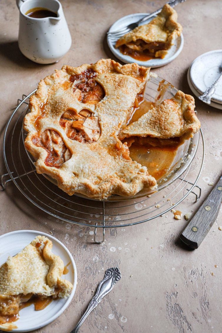 this salted caramel apple pie served in a glass pie dish with the salted caramel sauce