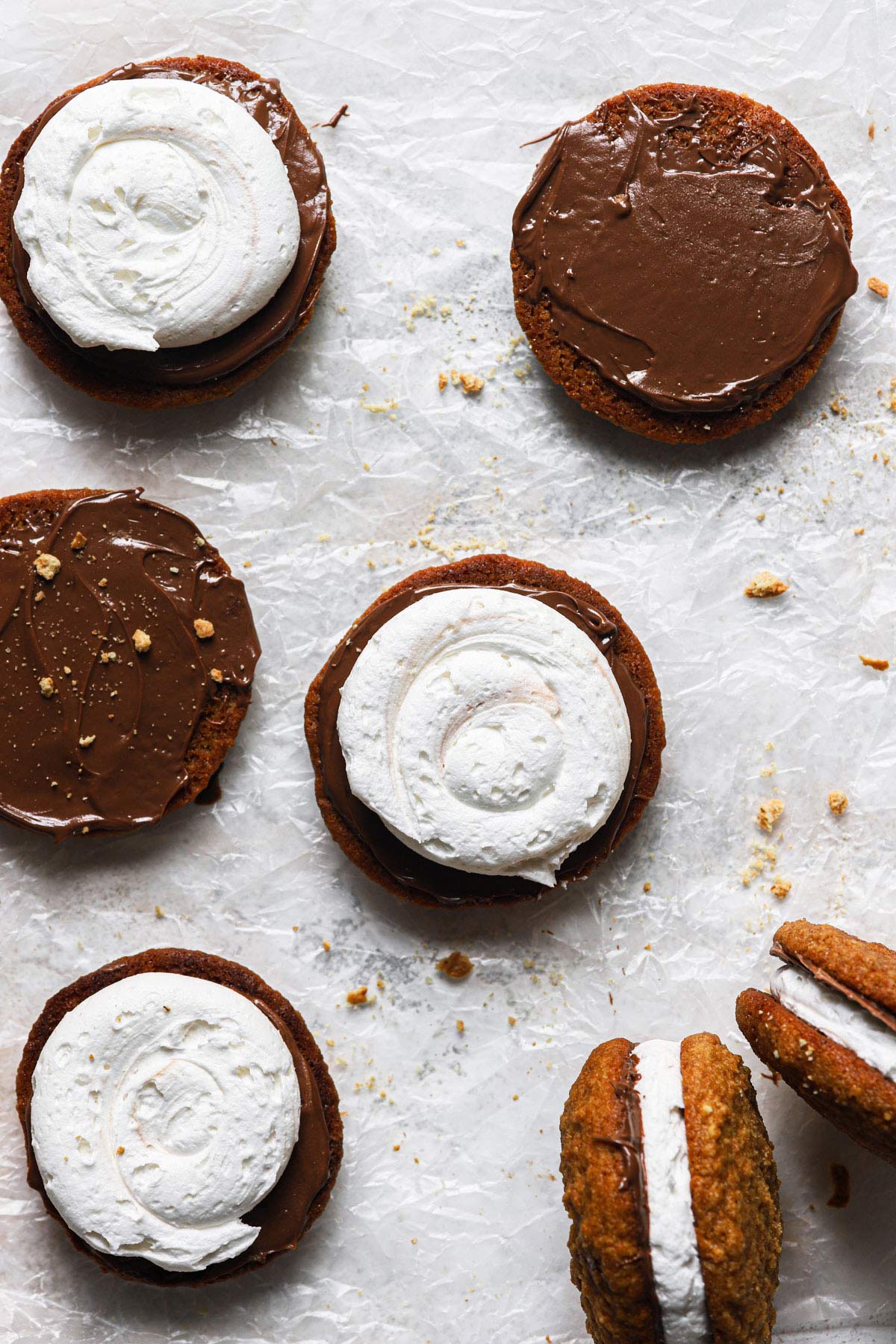 Whoopie pies being assembled; chocolate spread on half and marshmallow cream on top of chocolate.