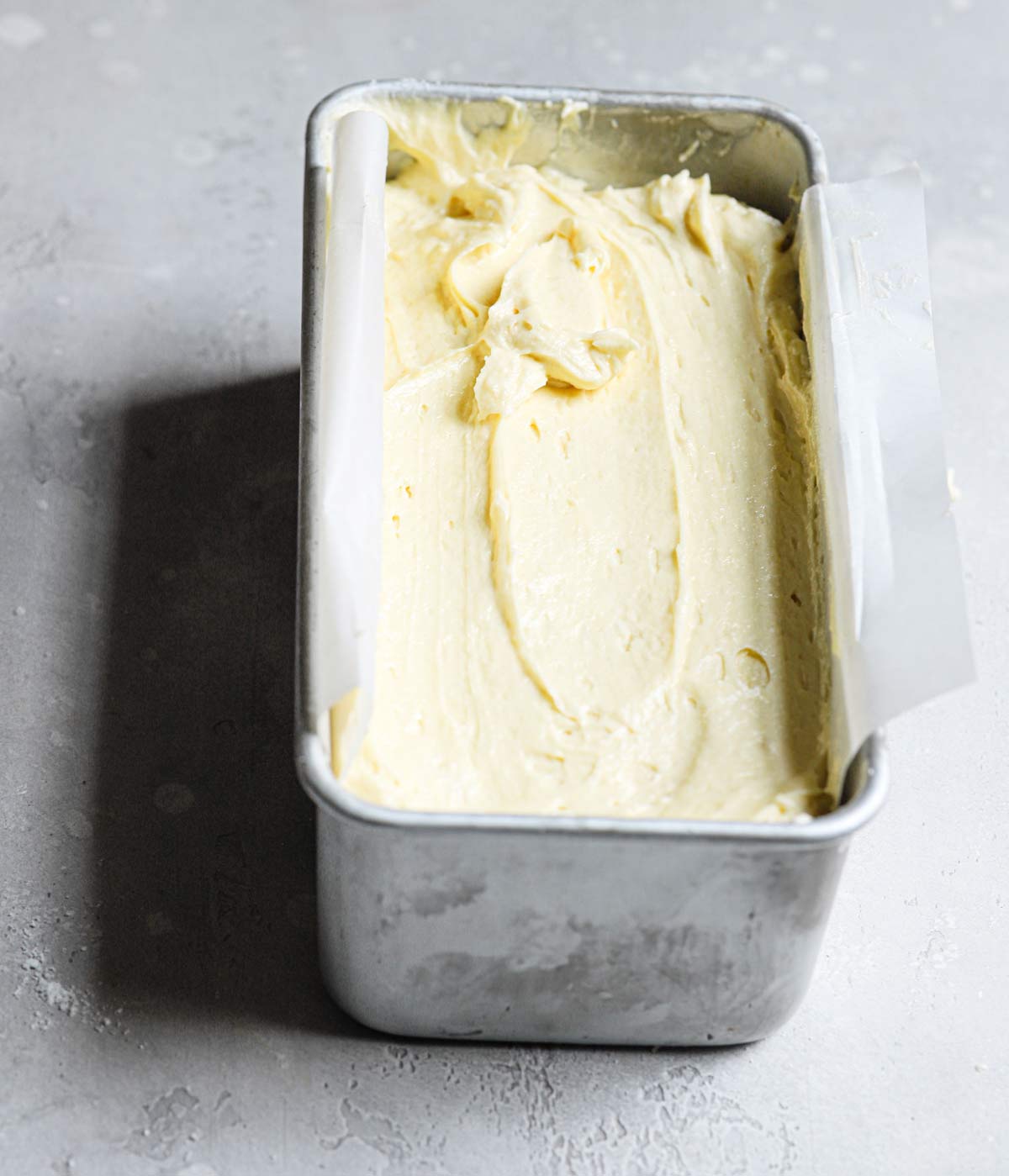 Pound cake batter in a silver loaf pan.