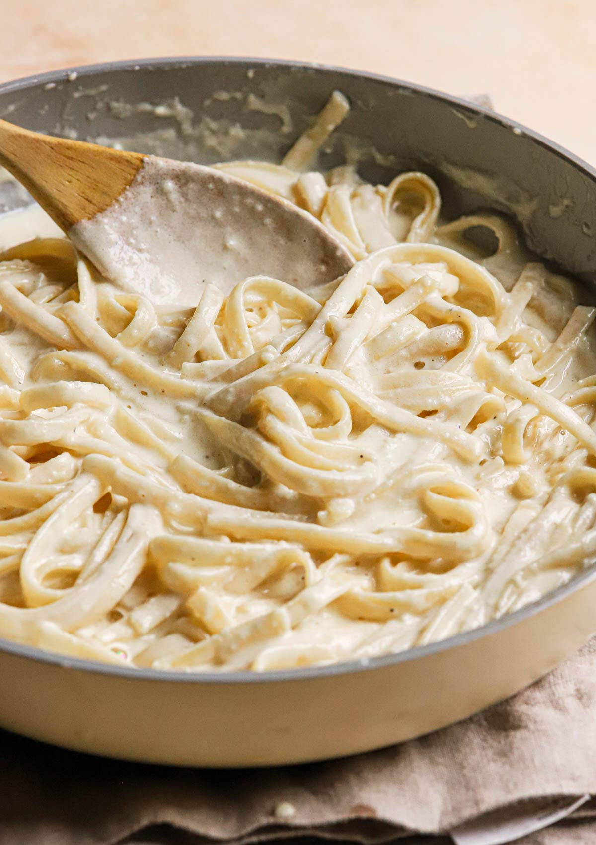 Saucepan full of fettuccine pasta tossed in creamy Alfredo sauce.