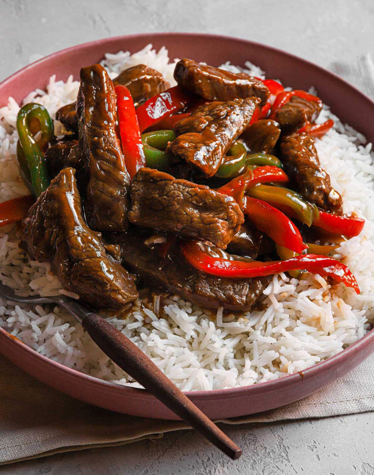 Pepper steak in a bowl served over white rice.