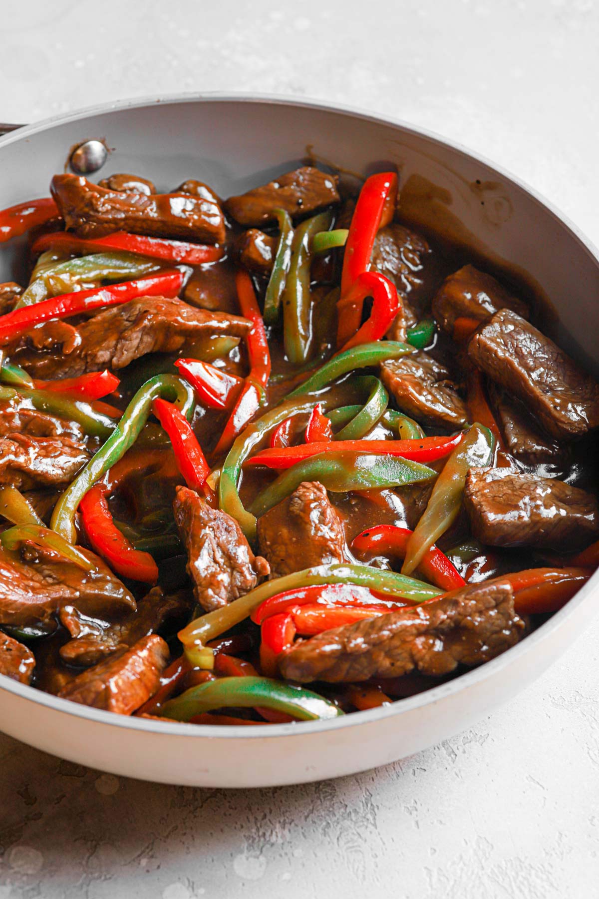 Pepper steak stir fry in a skillet coated in sauce.