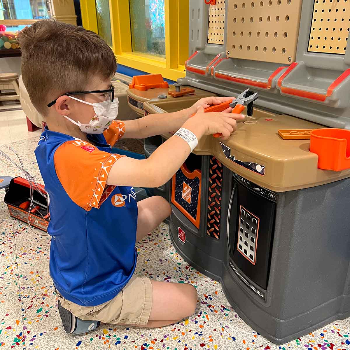 Boy playing with a toy work bench.