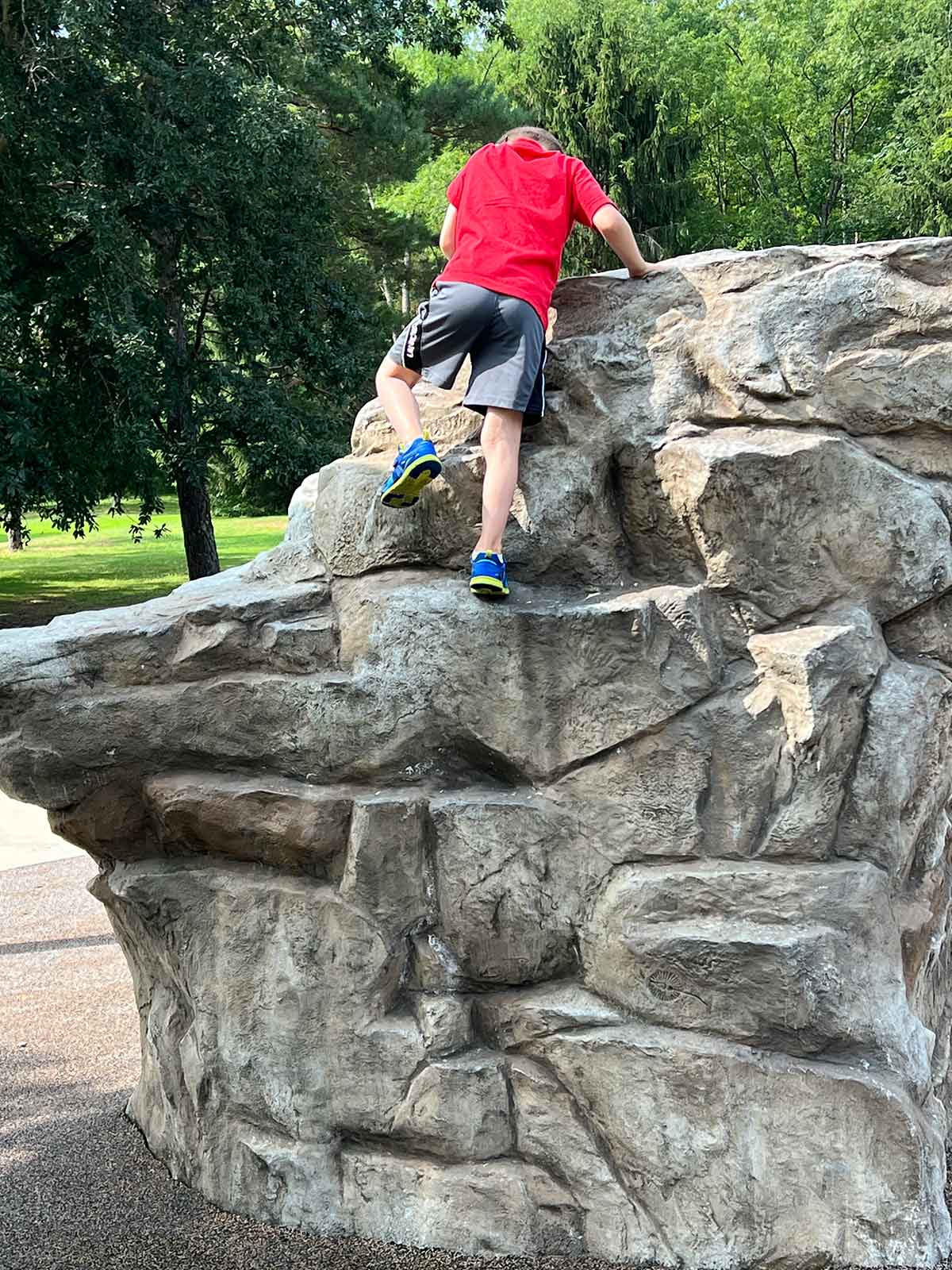 Boy climbing a rock structure at a playground.