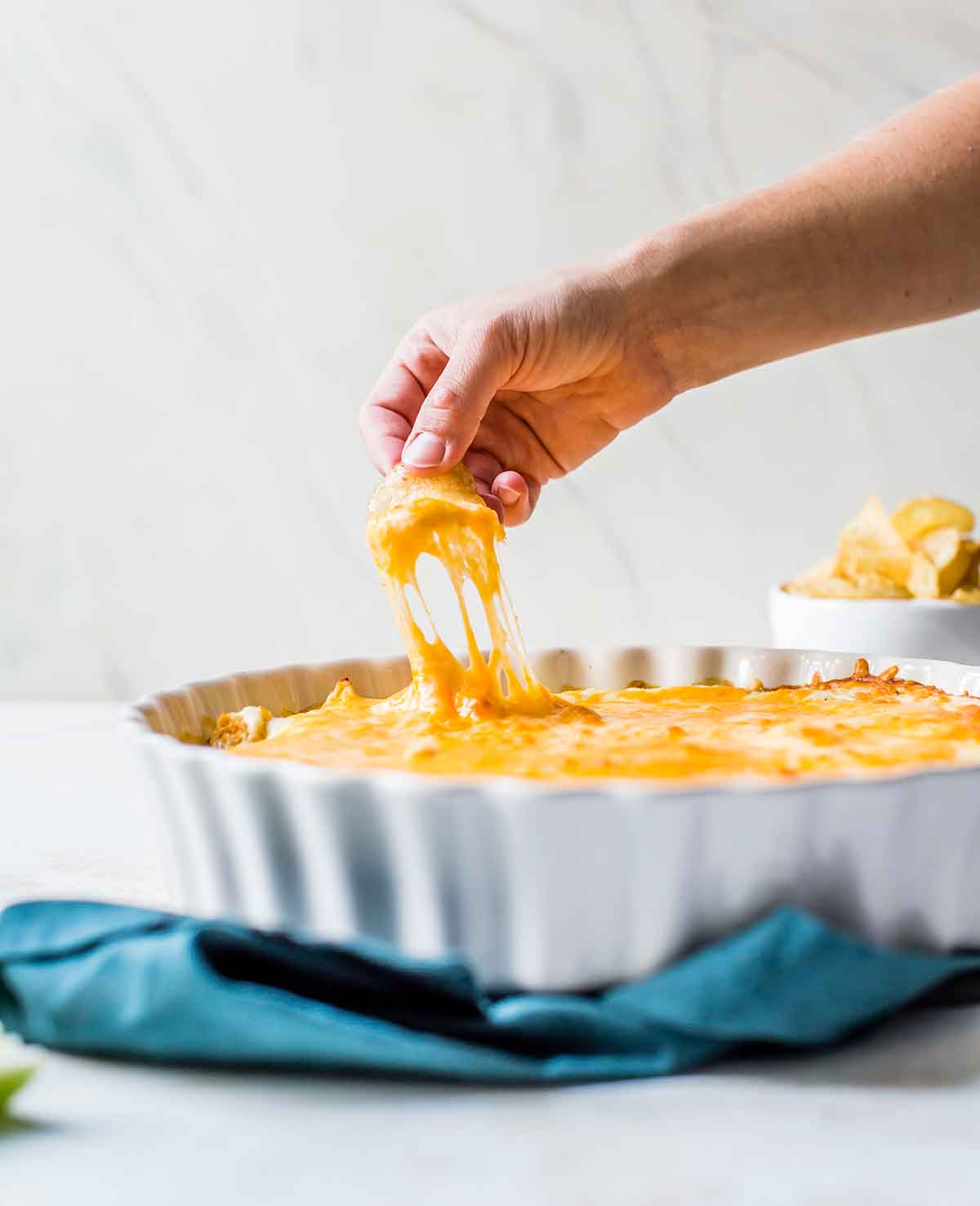 Someone pulling up a scoop of buffalo chicken dip on a potato chip.