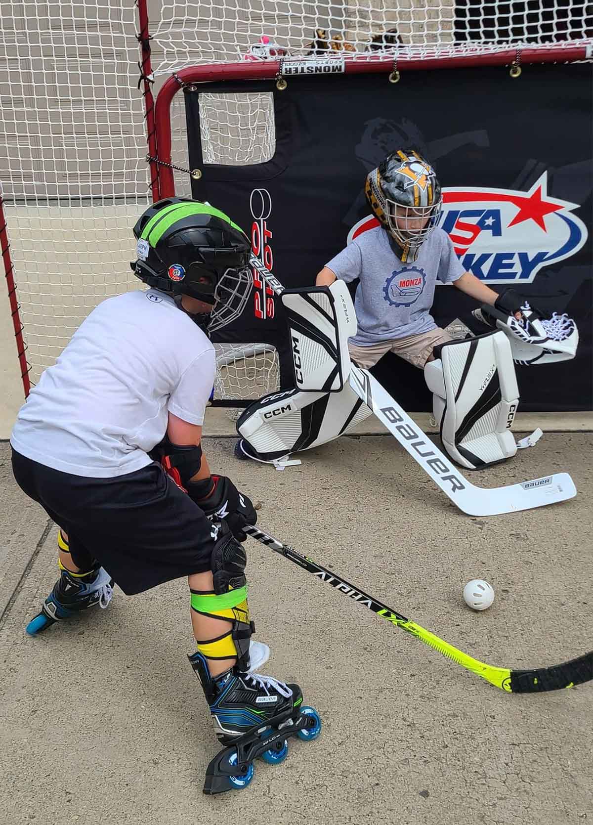 Two boys playing street hockey in a driveway.