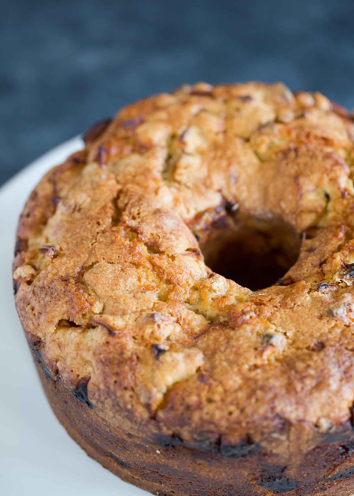A whole Jewish apple cake removed from the pan, and on a white cake platter.