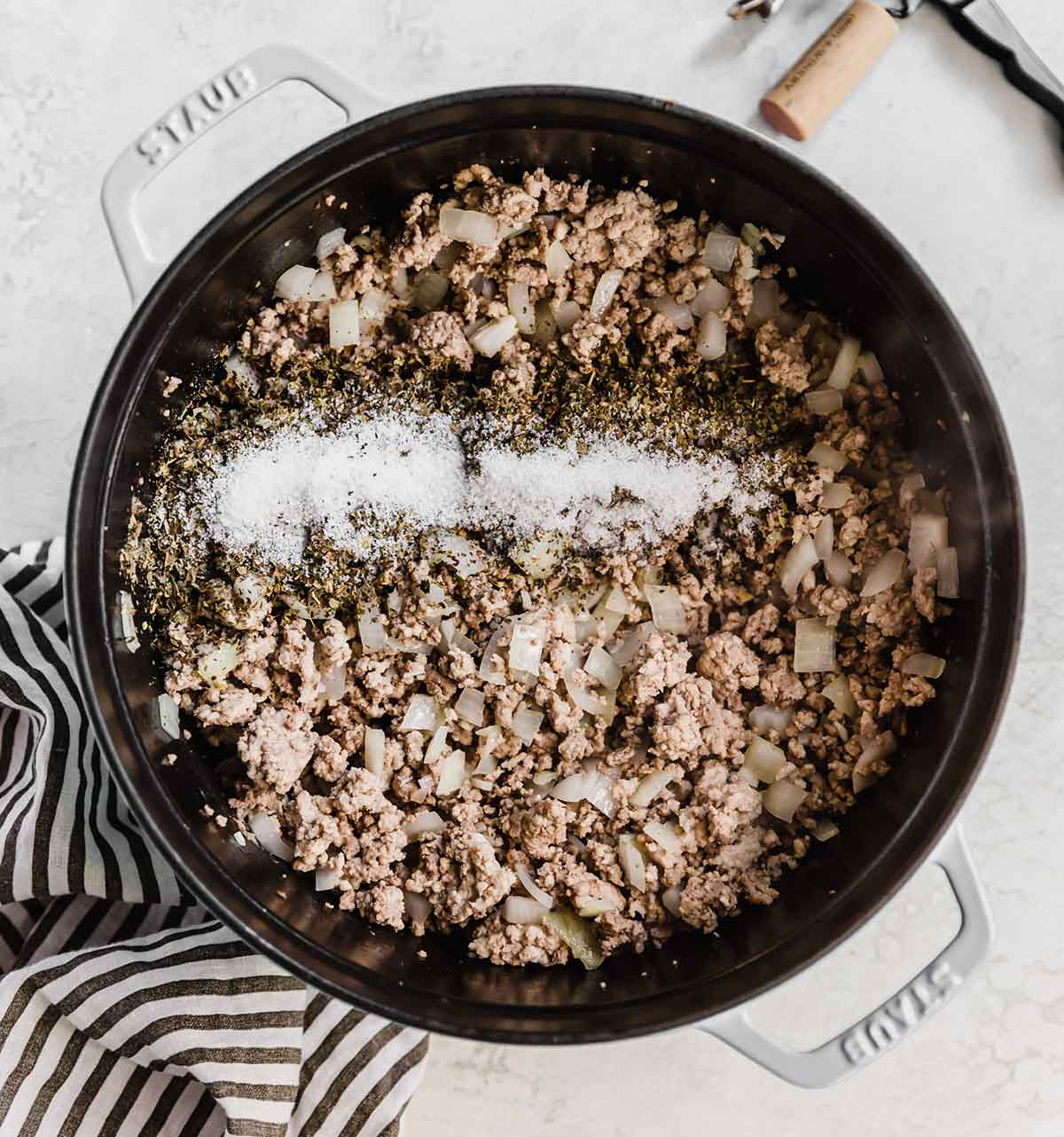 Overhead photo of a pot with browned meat, onions, garlic, and seasonings.
