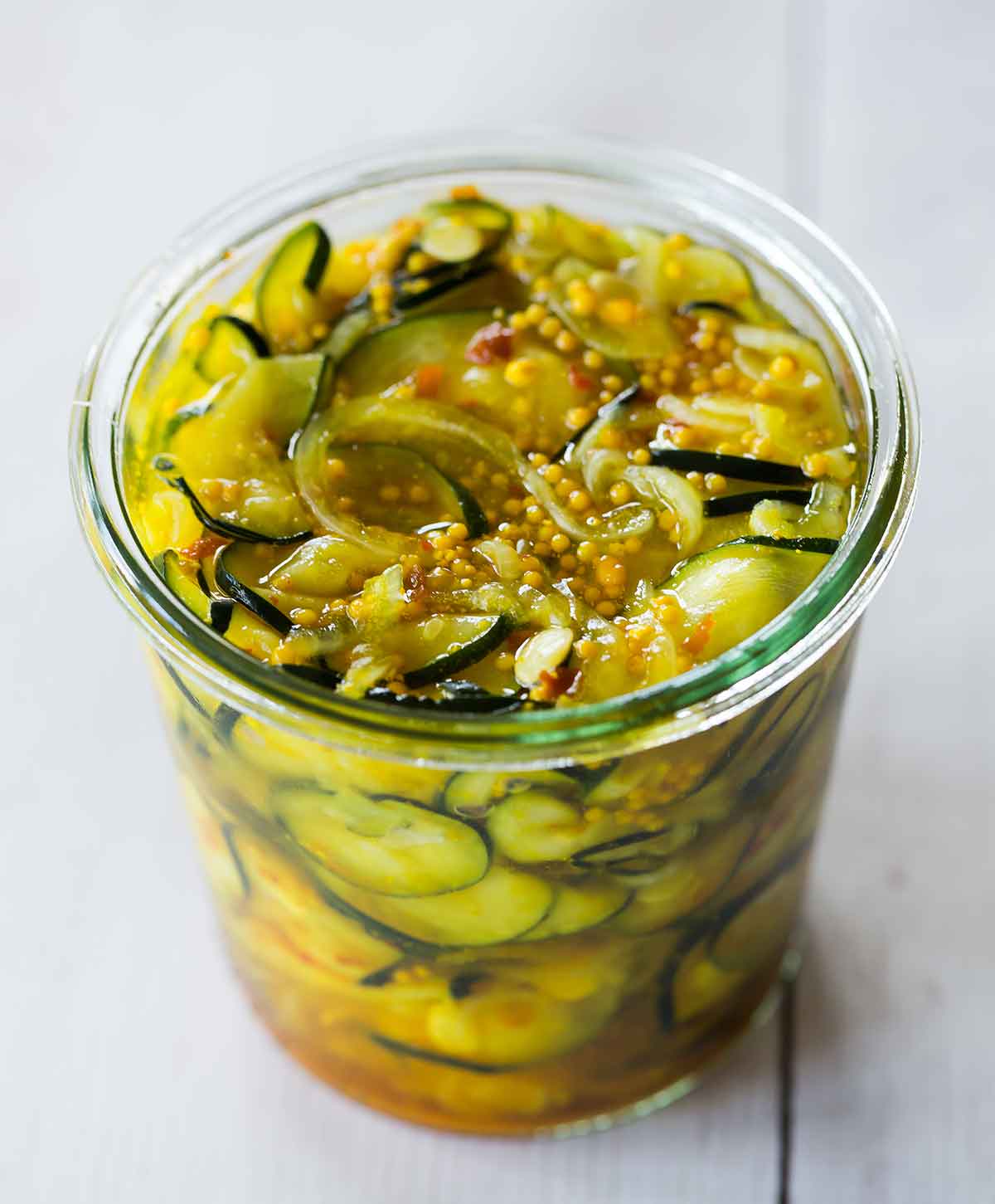 A glass jar of zucchini pickles without the lid on.