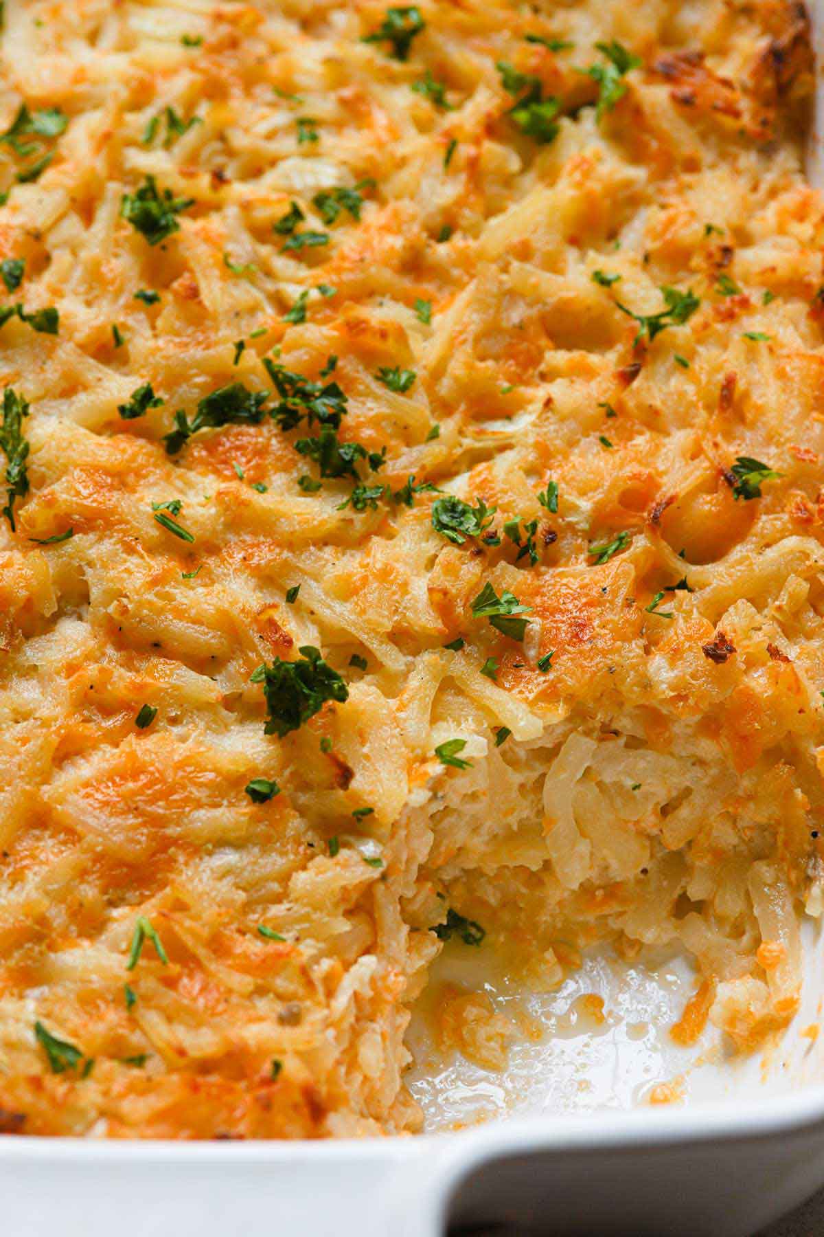 Overhead photo of hashbrown casserole with a large helping taken out of the corner.