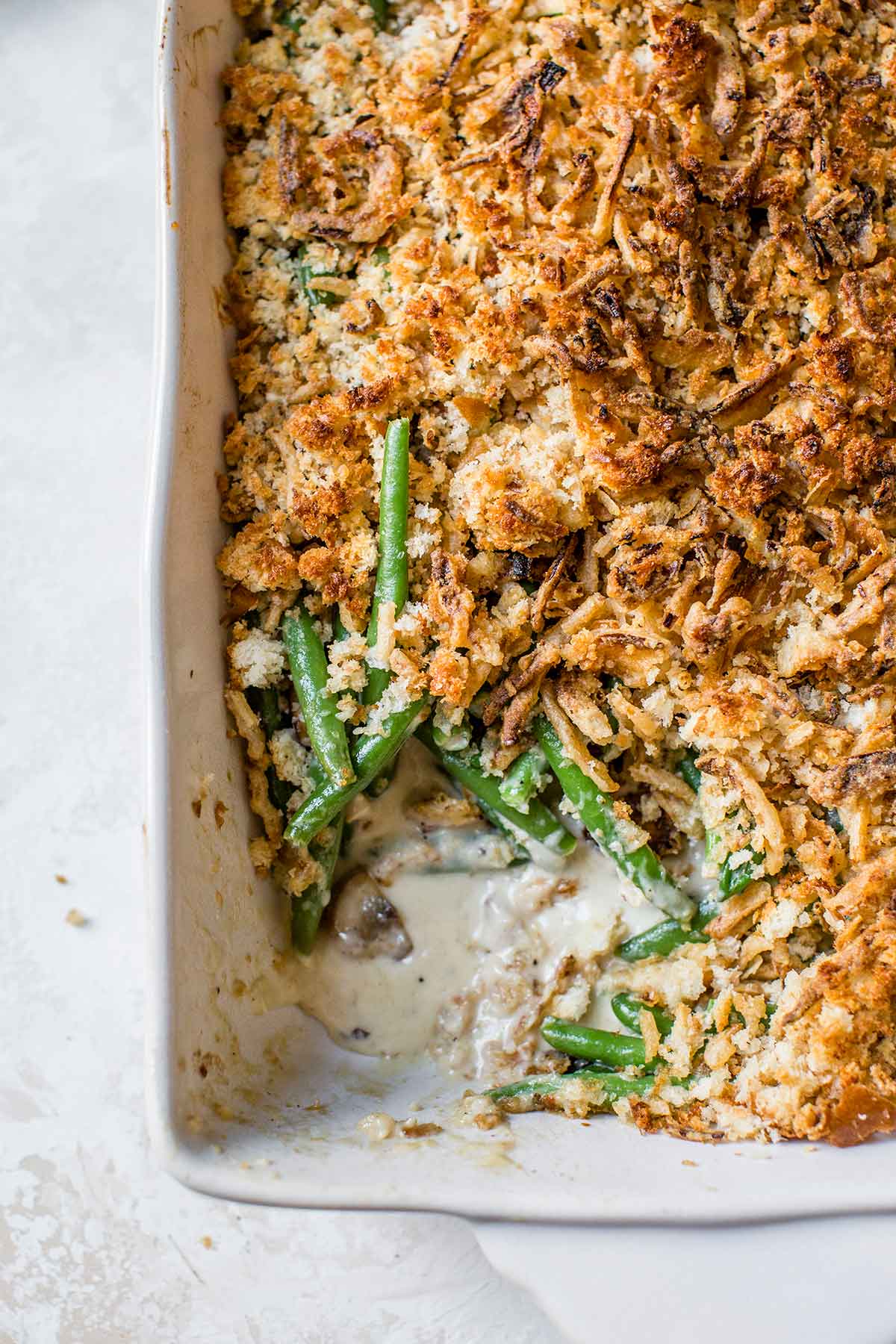 Overhead photo of green bean casserole in a baking dish with a corner scooped out.