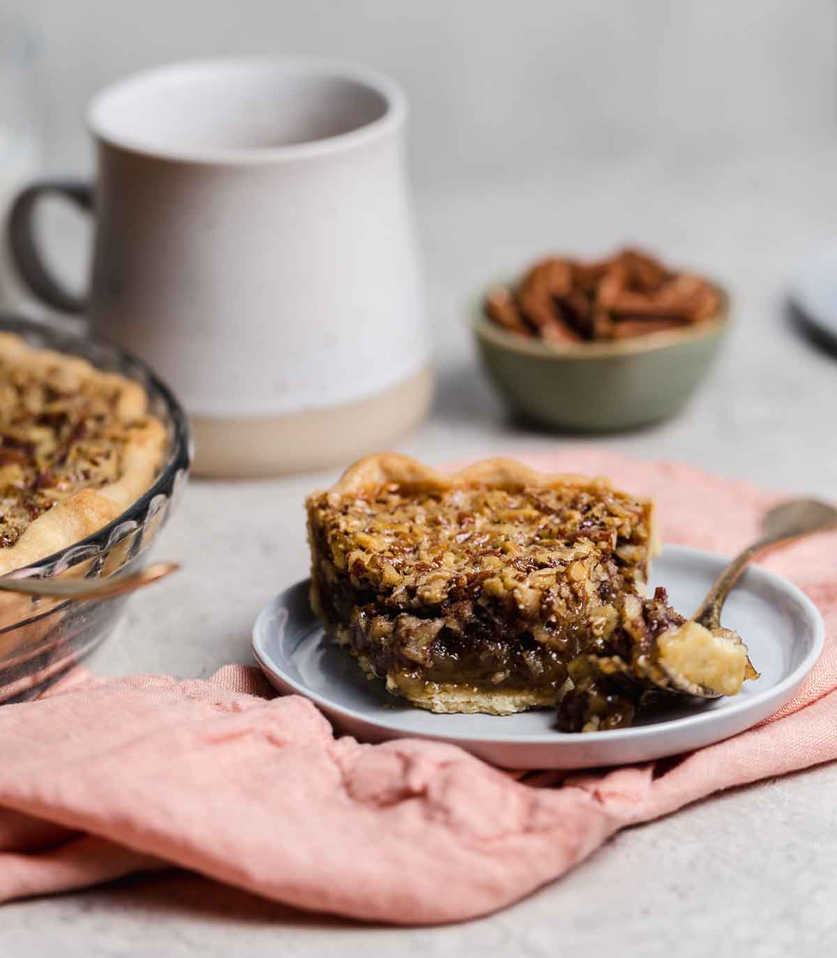 Slice of pecan pie on gray plate with forkful removed.