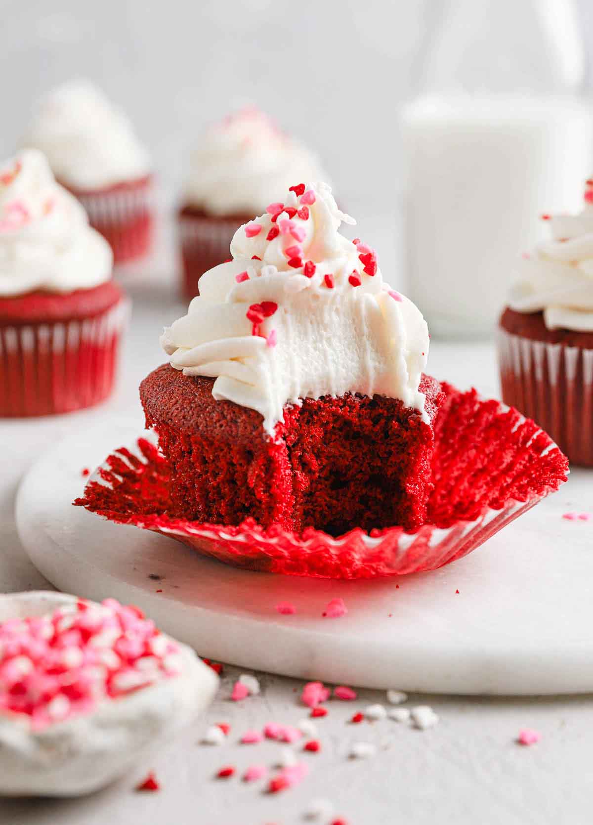Red velvet cupcake with liner pulled away and a bite taken out.