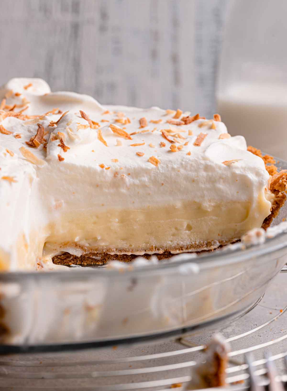Photo of coconut cream pie, taken from the side, with a slice removed from the pie plate.