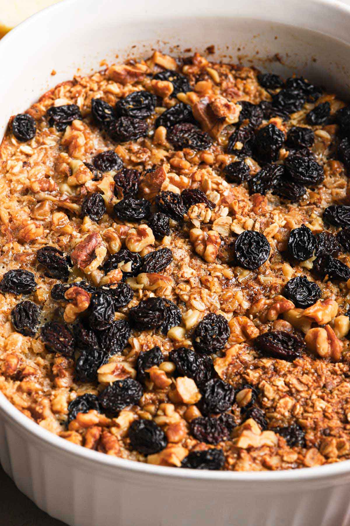 Close up photo of pan of baked oatmeal with walnuts and raisins on top.