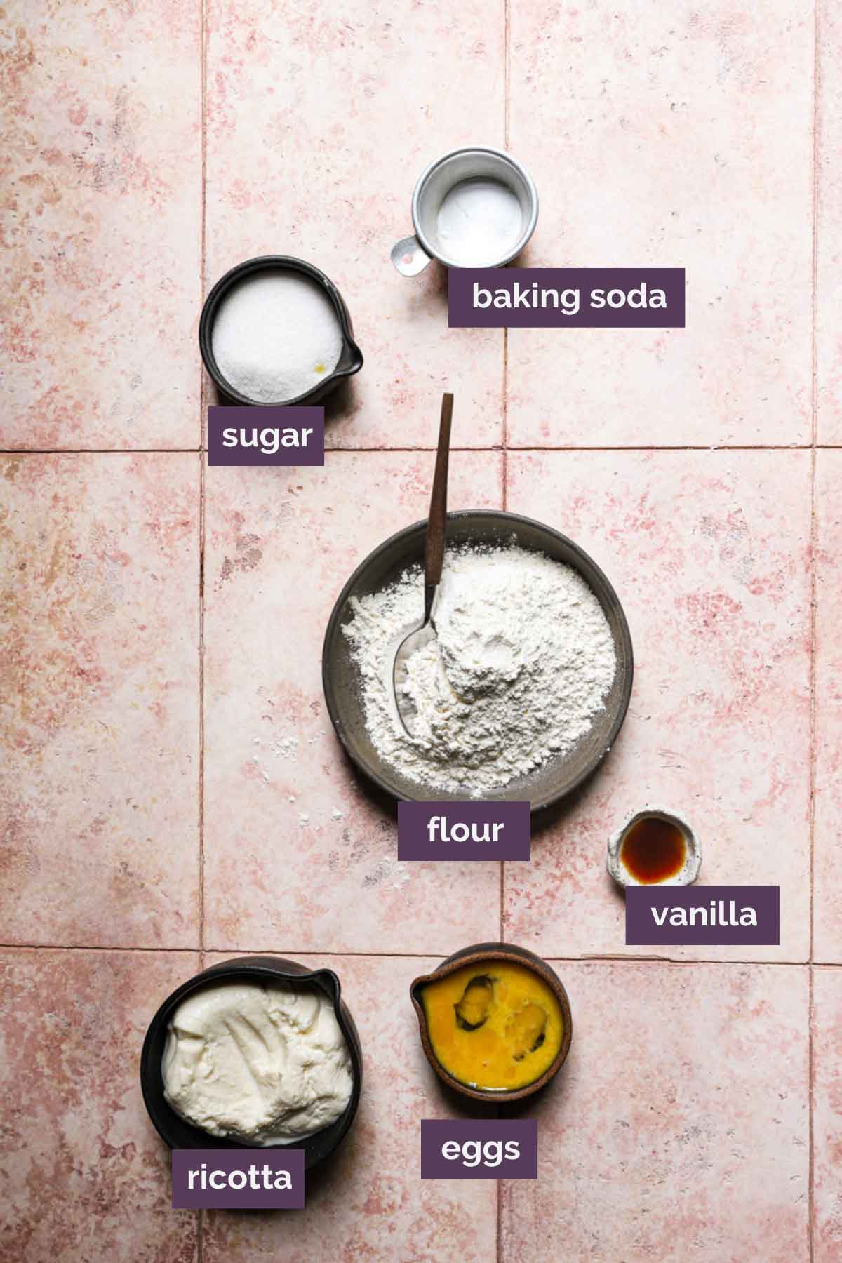 Ingredients for zeppole prepped and labeled on a light pink background.