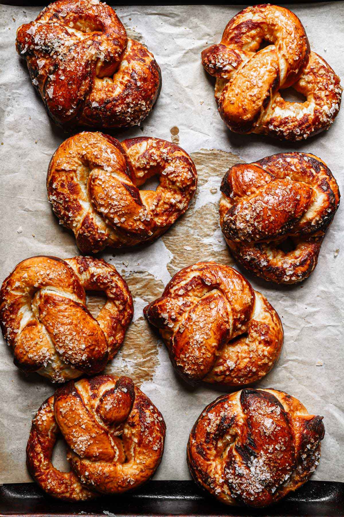 Freshly baked soft pretzels on parchment paper.