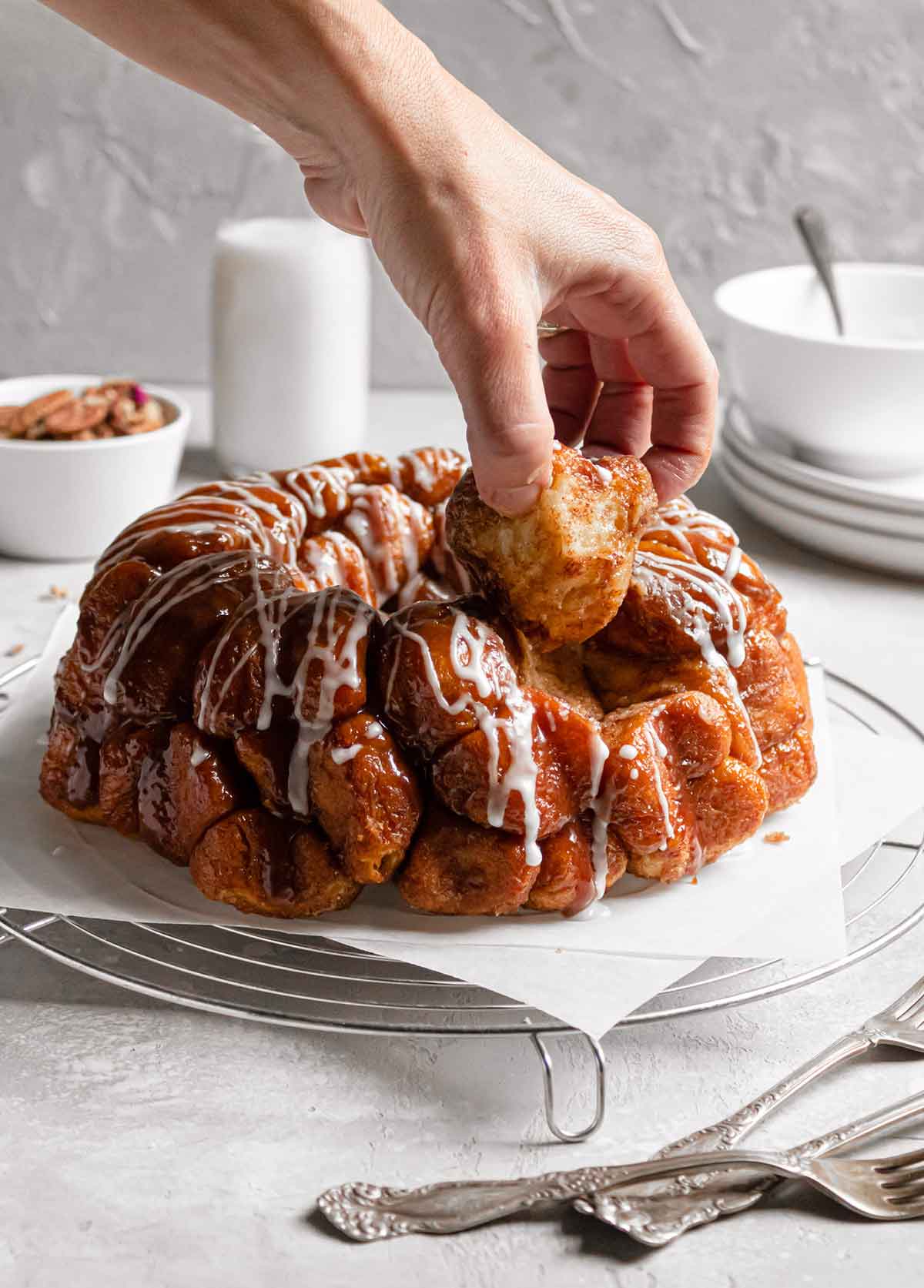 A hand pulling a piece of monkey bread off of the loaf.