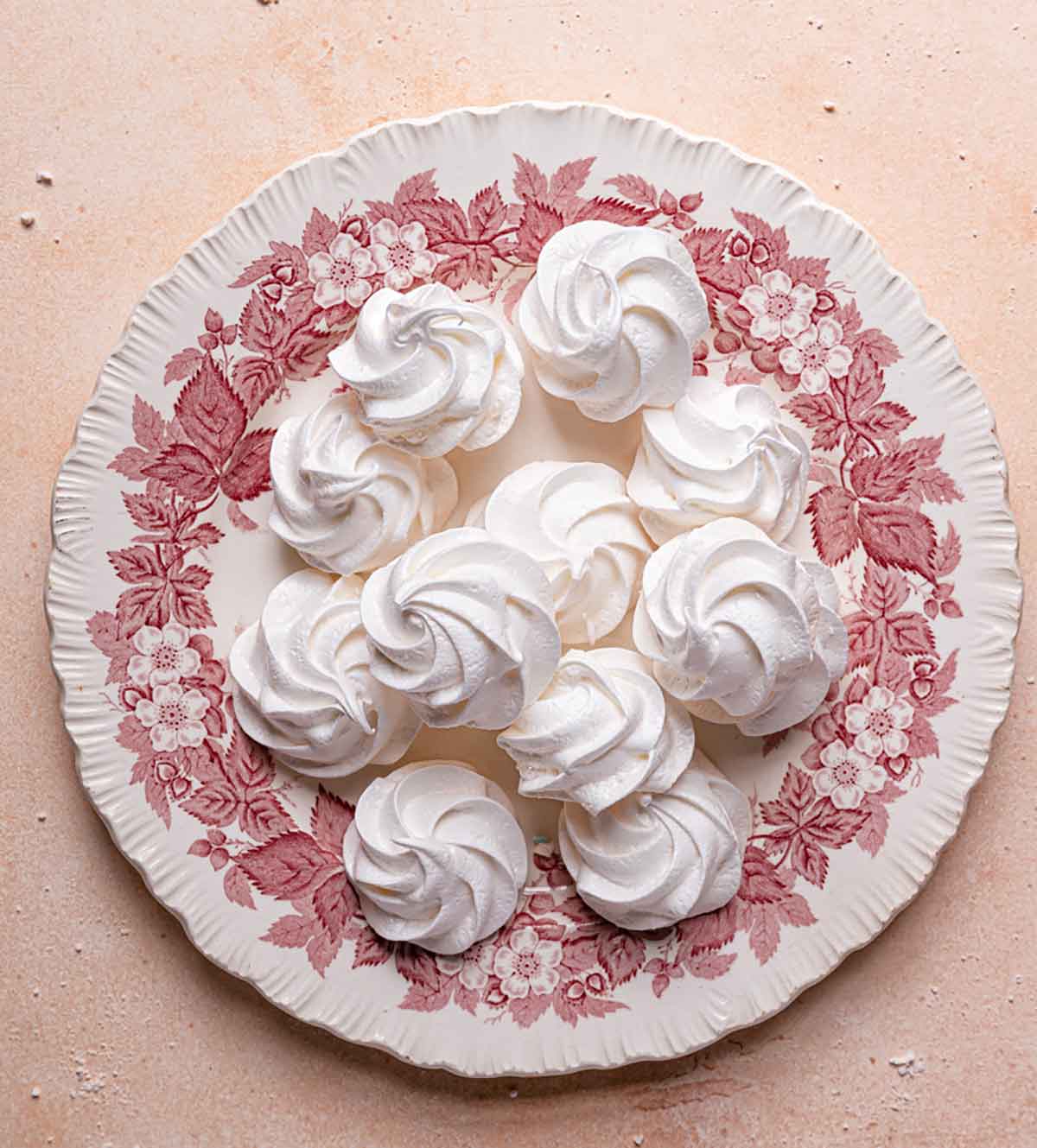 Meringue cookies on a plate with pink and white designs.