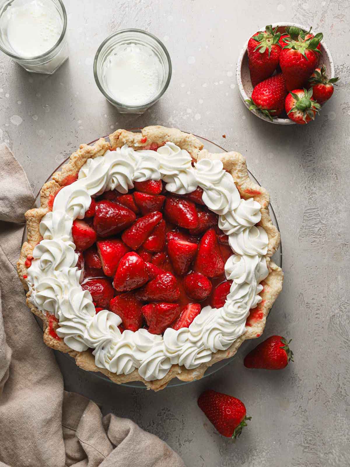 Overhead photo of fully assembled strawberry pie with small bowl of strawberries off to the side.