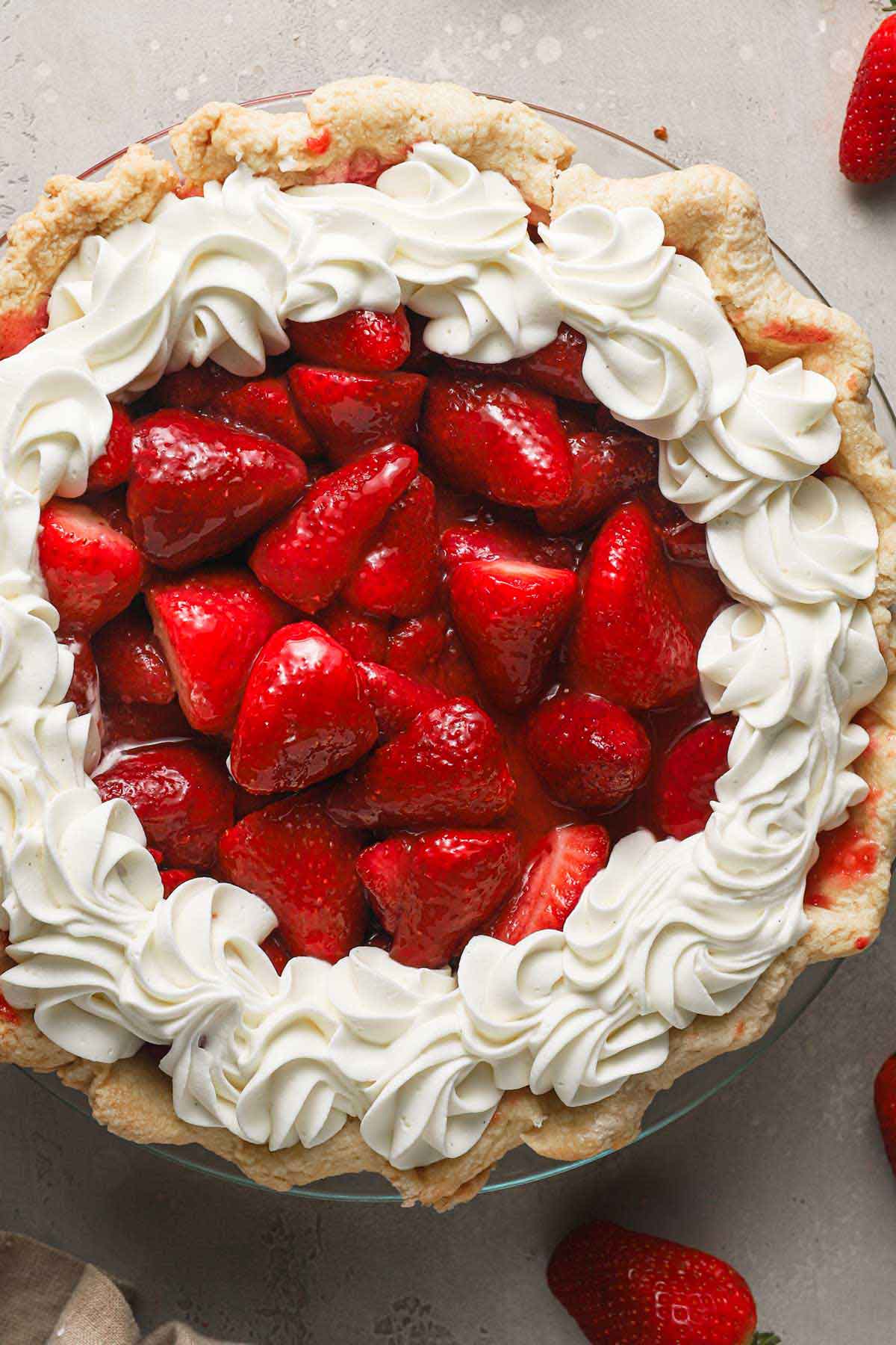 Overhead photo of a strawberry pie with whipped cream piped around the border.