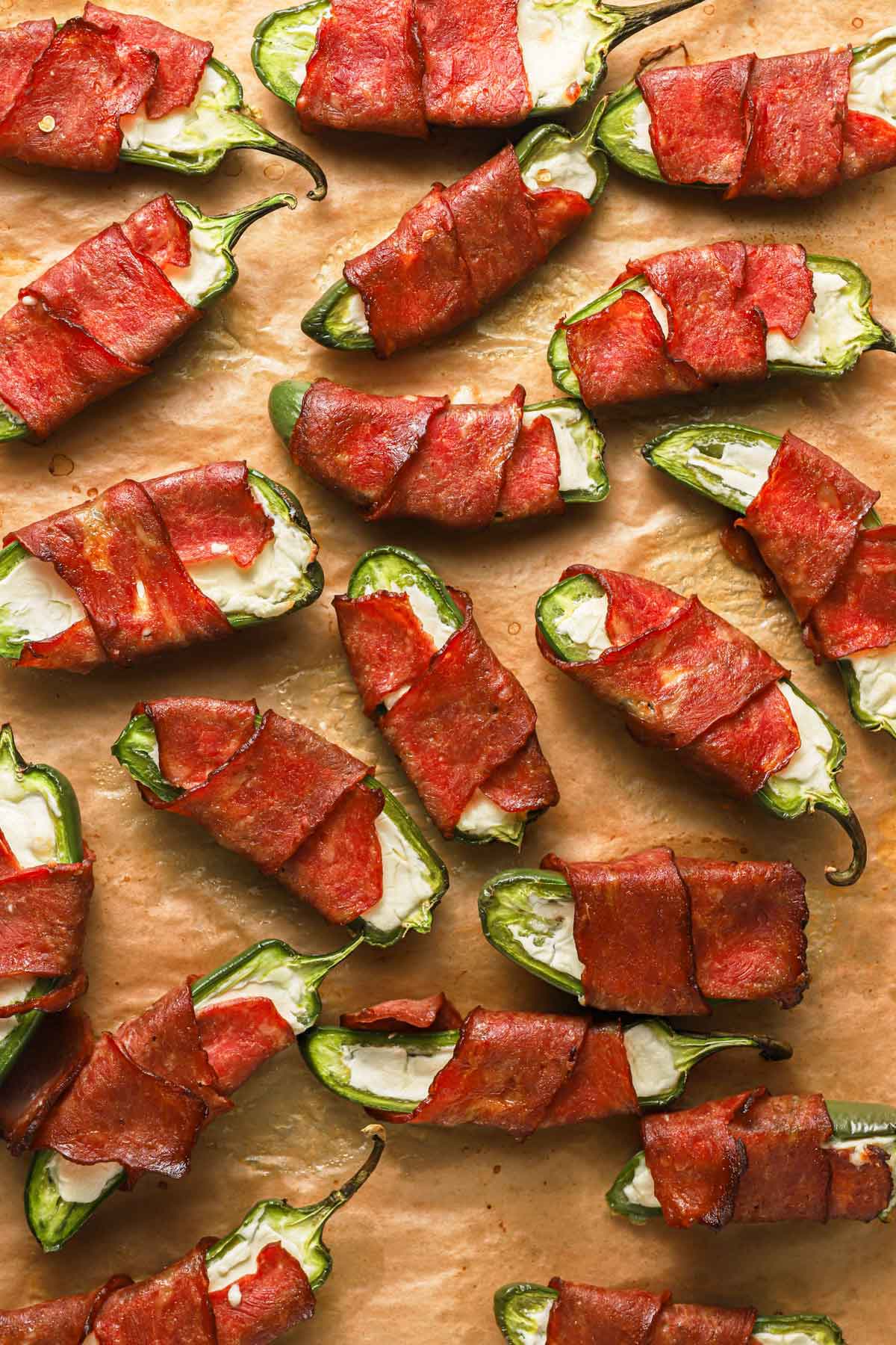 Baking sheet covered in parchment paper with bacon-wrapped jalapeno poppers fresh from the oven.