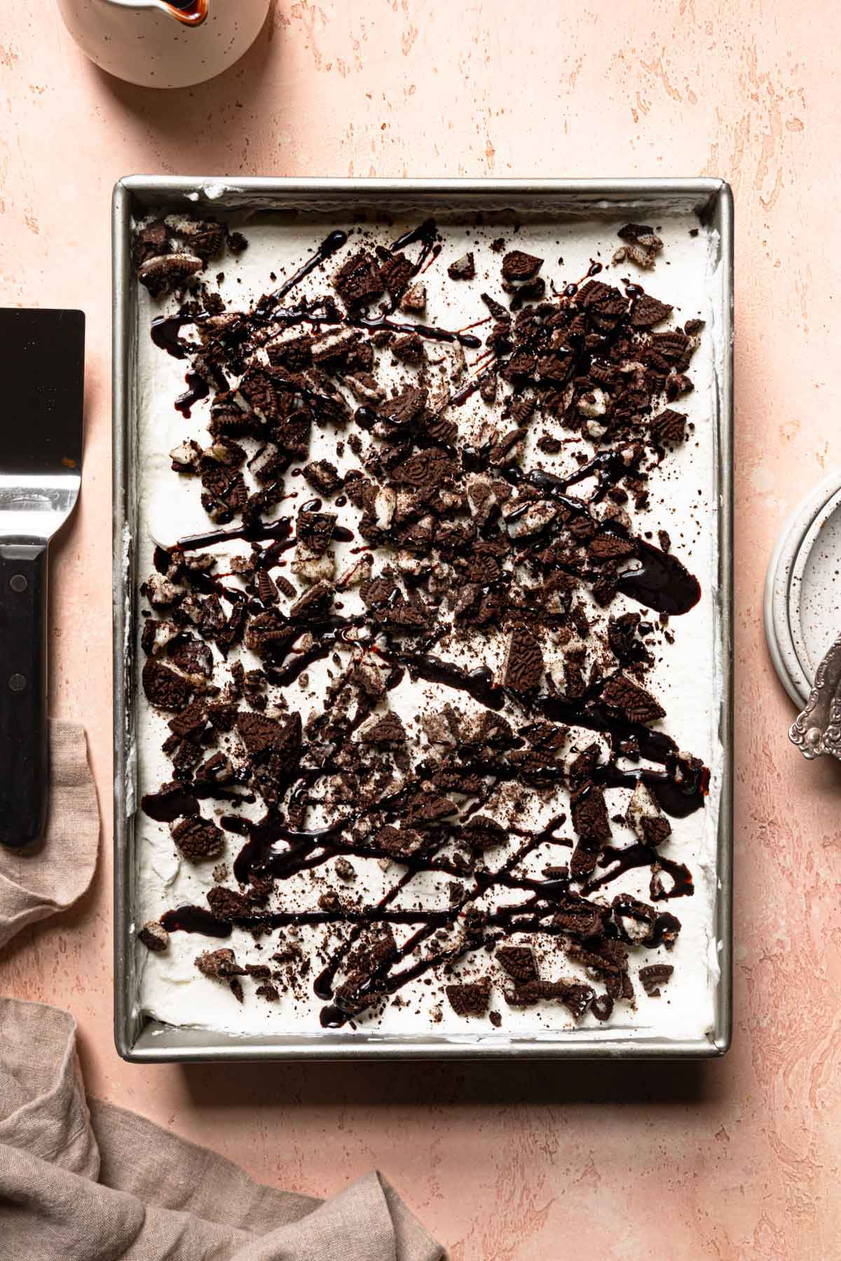 Overhead photo of baking dish topped with a layer of Cool Whip then crushed Oreos and hot fudge sauce.