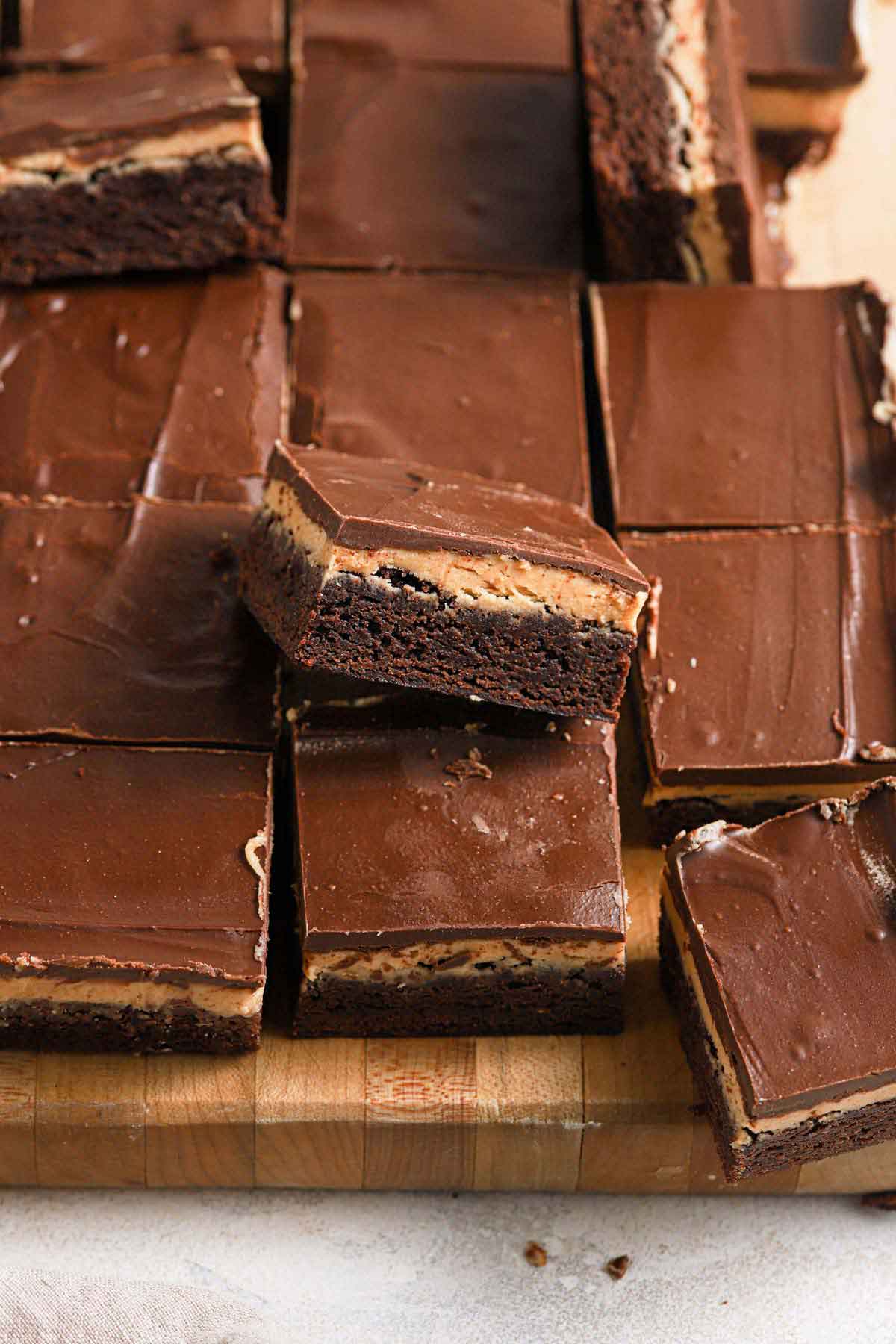 Buckeye brownies cut into squares on a cutting board with some of them propped up on their sides.