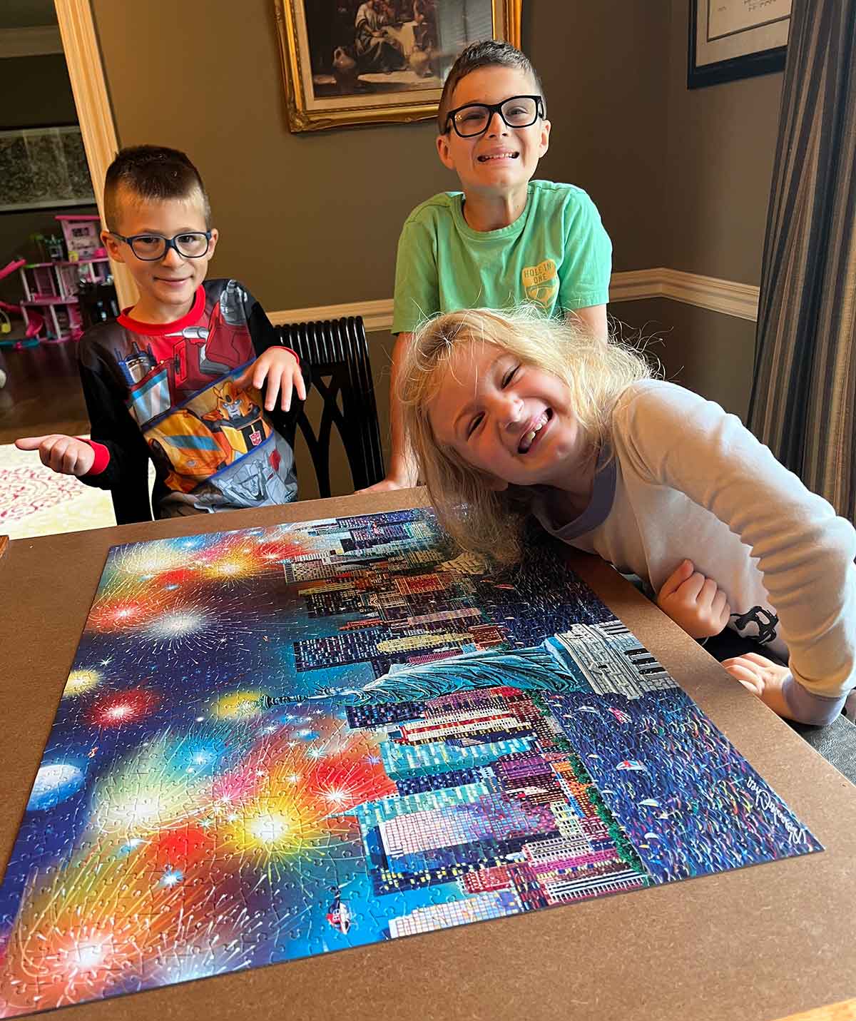 Two boys and a girl leaning over a completed jigsaw puzzle.