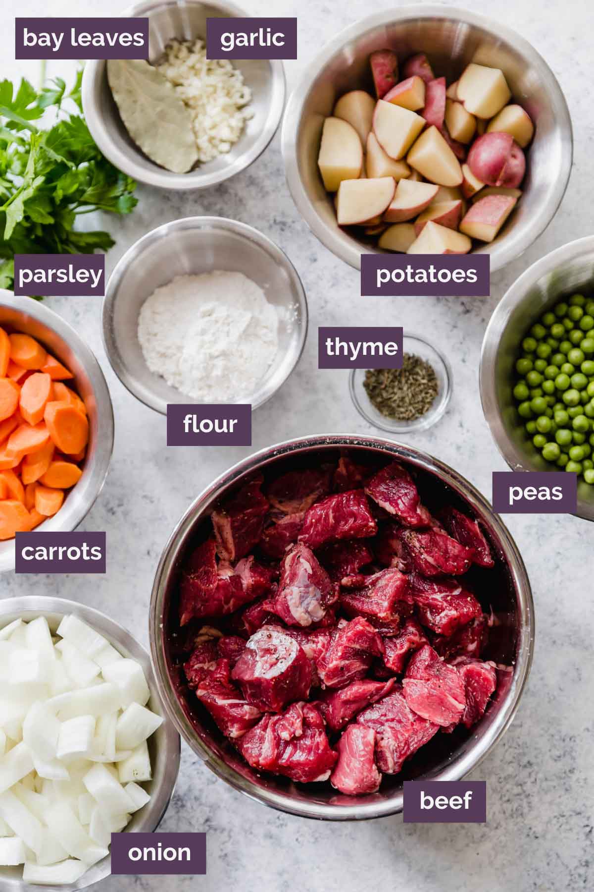 Ingredients for beef stew prepped and labeled on a counter.