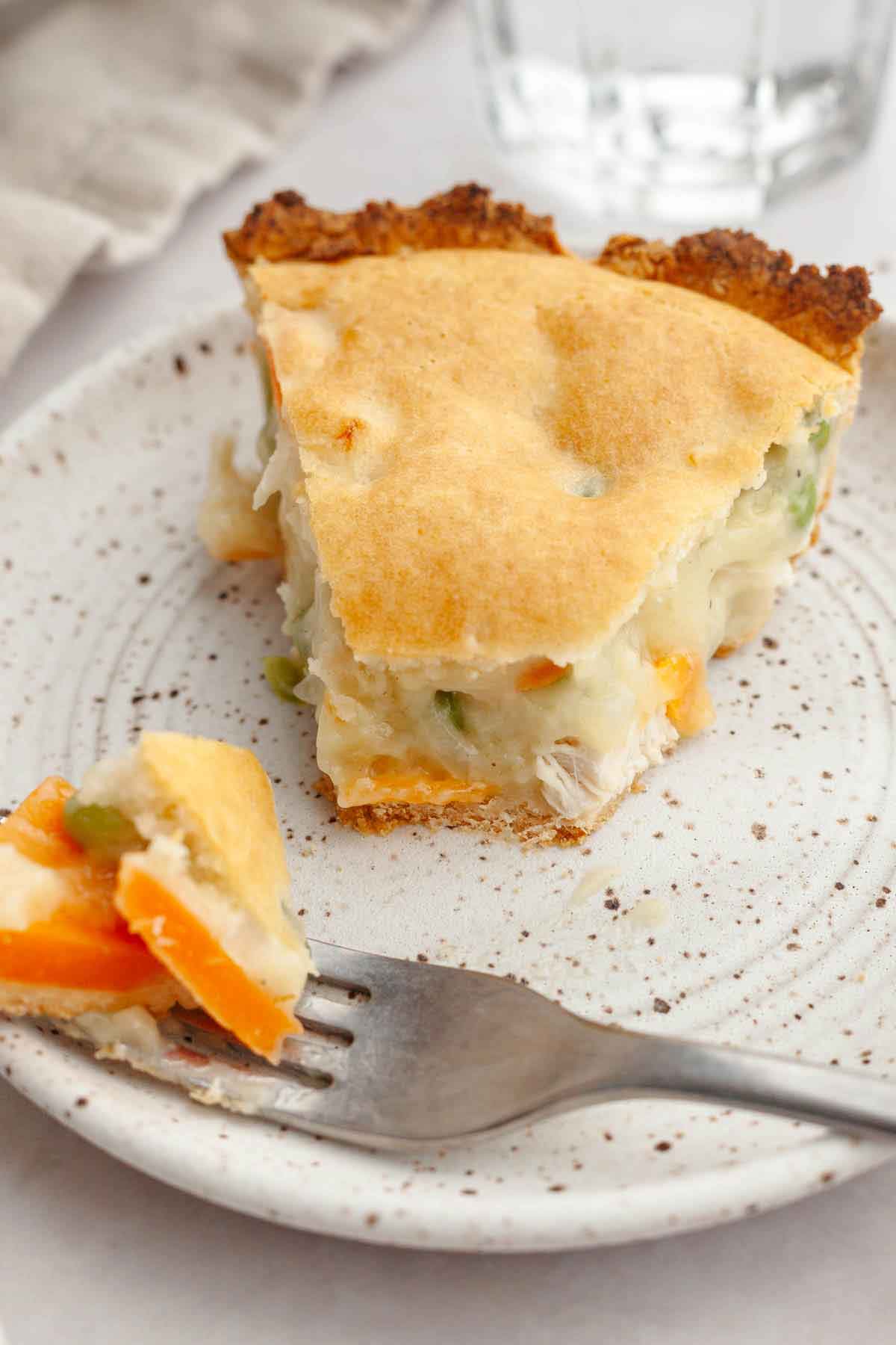 Slice of chicken pot pie on a plate with a forkful taken off.