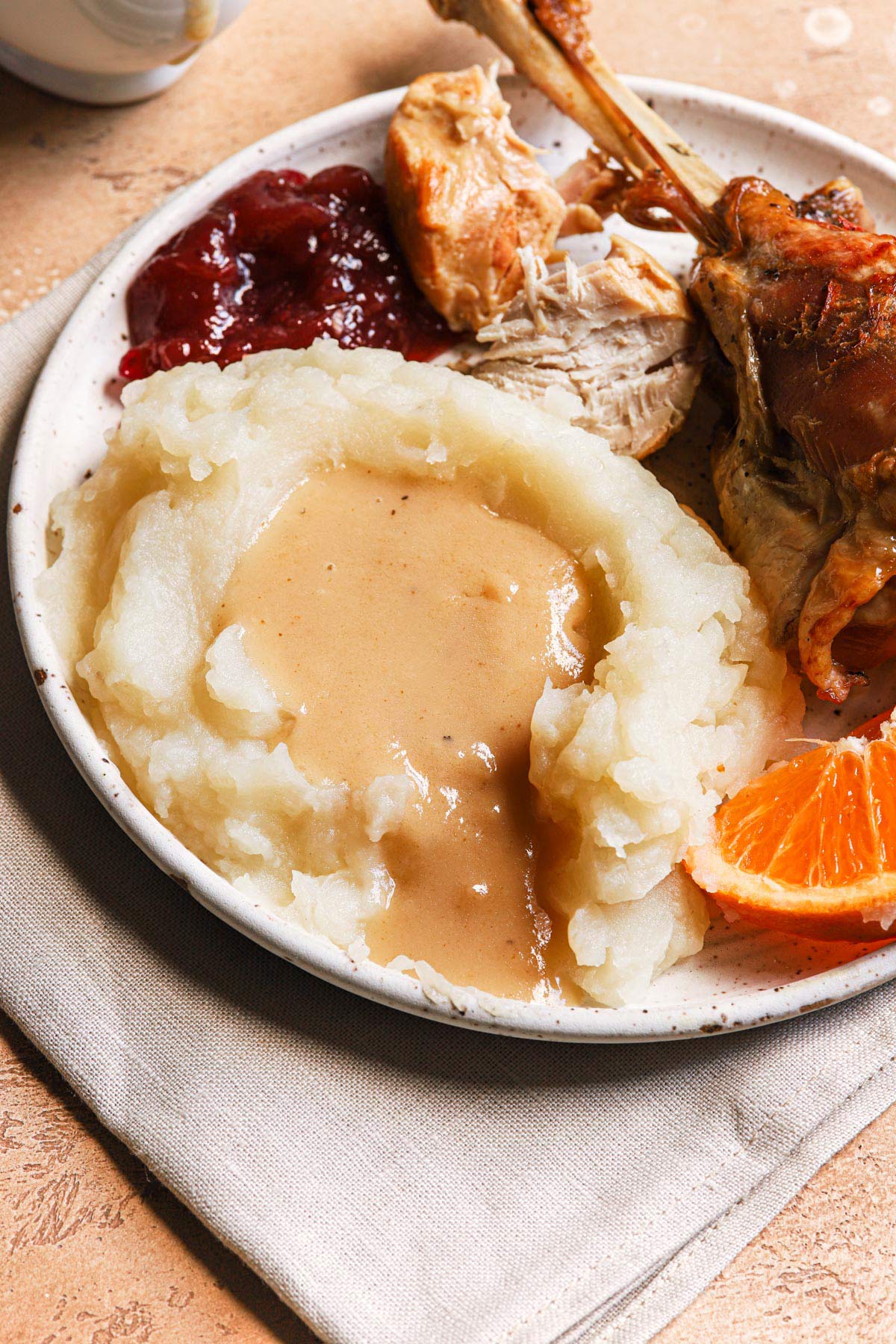 Plate of Thanksgiving food - turkey, cranberry sauce, mashed potatoes, and make ahead turkey gravy.