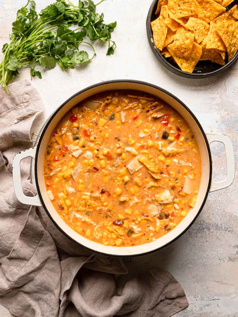 Overhead photo of a pot of chicken corn chowder with tortilla chips and cilantro in the background.