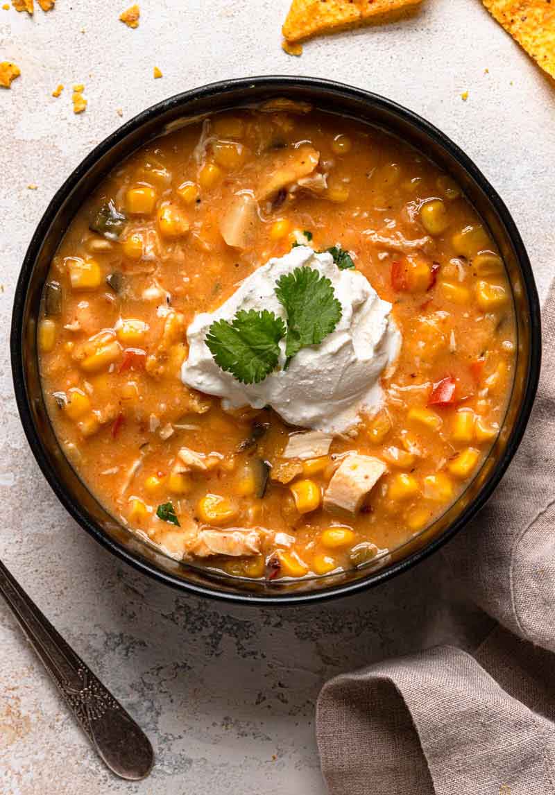 Overhead photo of a bowl of chipotle chicken and corn chowder topped with a dollop of sour cream and cilantro.