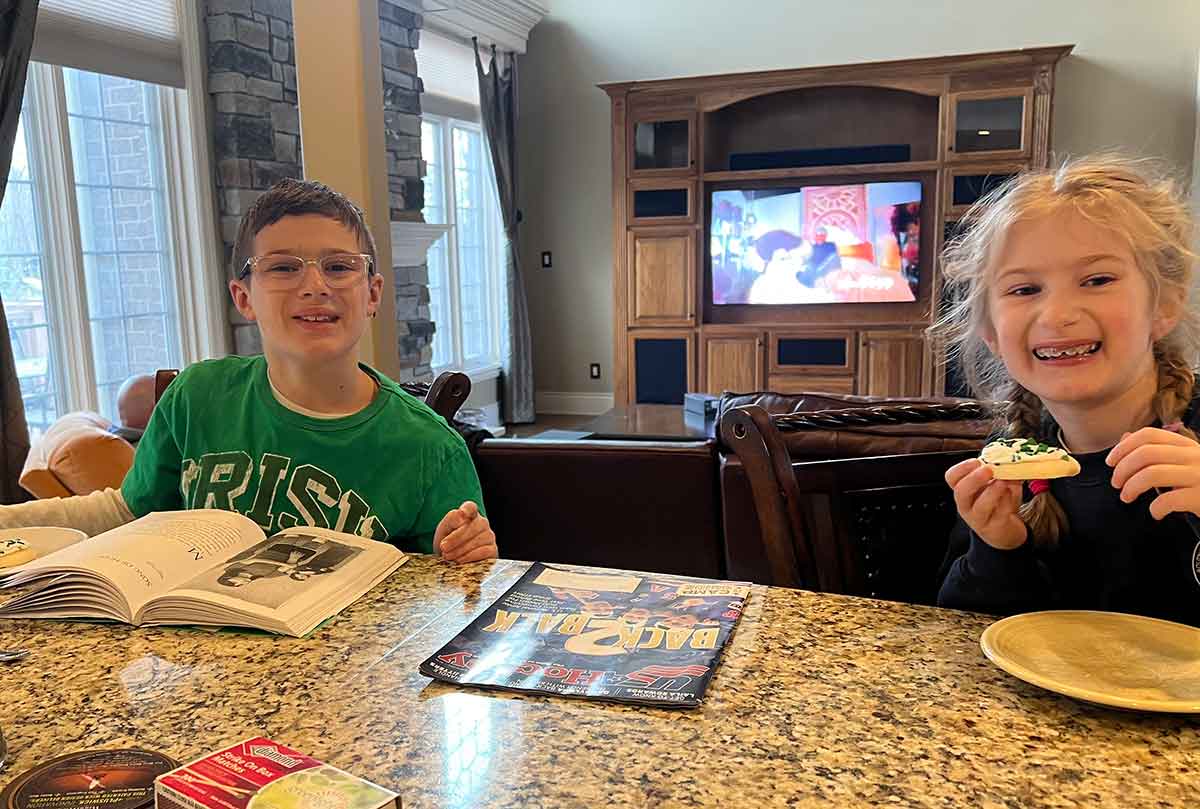 Boy and girl eating at a countertop and smiling at the camera.