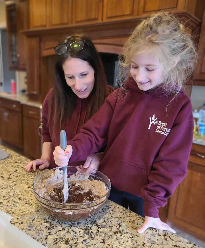 Woman and daughter standing at a kitchen counter making brownie mix.