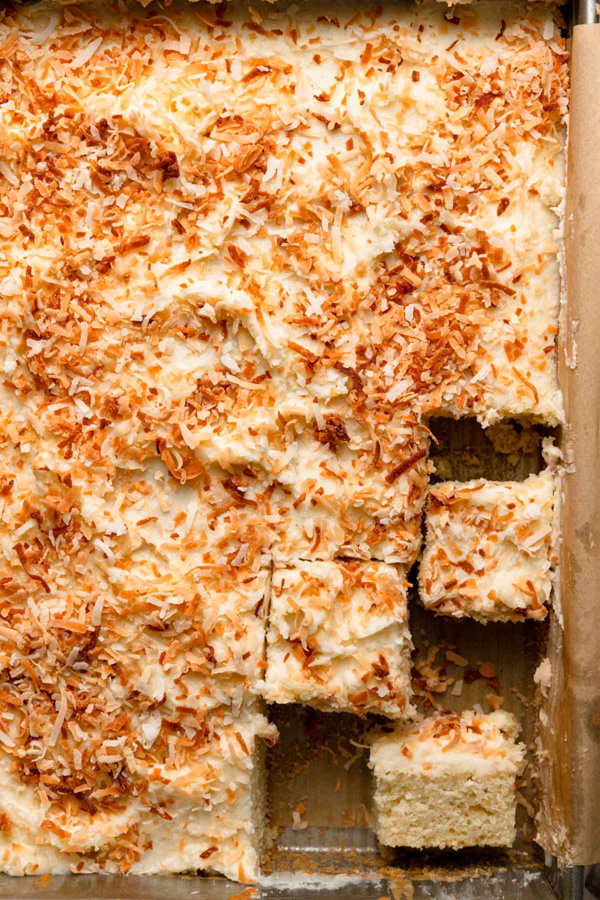 Overhead photo of coconut cake still in the pan with one slice on its side.