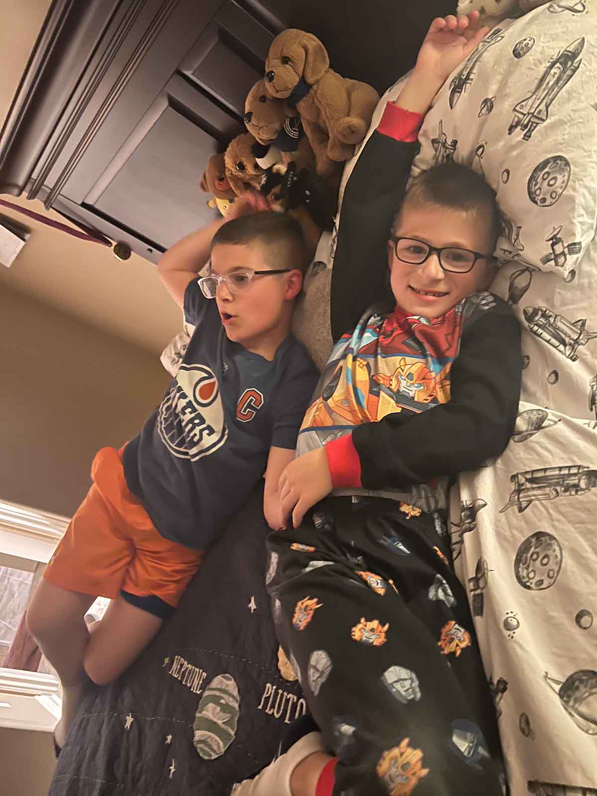 Two boys relaxing on a bed next to each other.