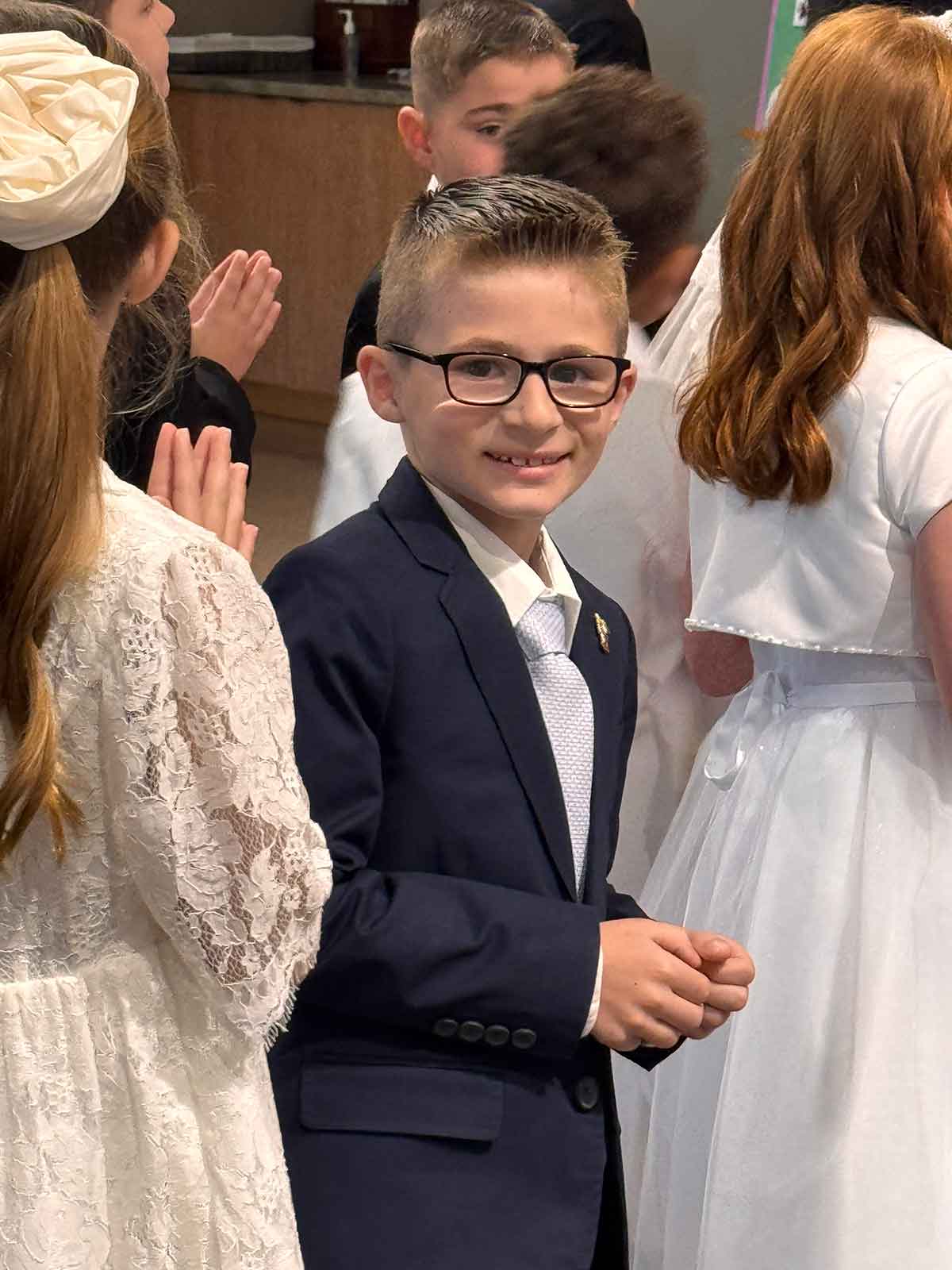 Little boy in a suit smiling at the camera.